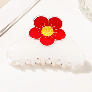 Gros plan d'une pince à cheveux blanche translucide ornée d'une fleur rouge avec cœur jaune