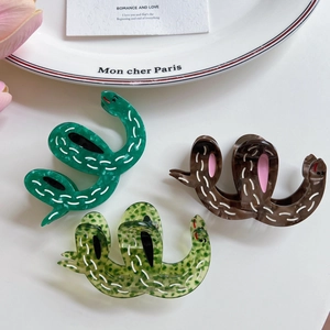 Snake shaped acetate hair claws in green and brown patterns with spotted details