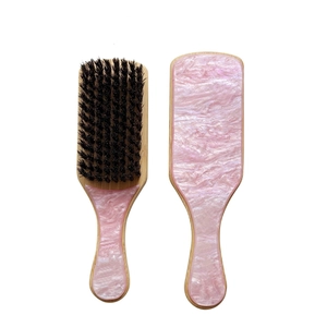 Détail macro d'une brosse en bois avec incrustation résine marbre rose et poils noirs