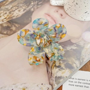 Détail d'une pince à cheveux florale avec texture marbrée colorée sur un magazine