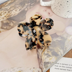 Gros plan détaillé d'une pince à cheveux fleur en acétate écaille sur un bureau élégant
