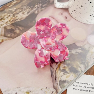 Vue détaillée de la pince à cheveux fleur rose en acétate avec une texture lisse et brillante