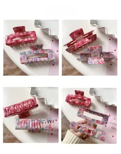 Detail view of rectangular acrylic hair claws with colorful heart patterns and metal springs