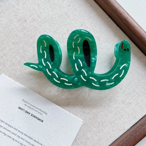 Detail view of a green marbled acetate hair claw clip in a unique curved snake shape