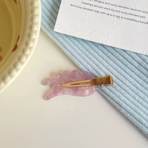 Close-up of translucent purple wing hair clip with rhinestones on a knitted background