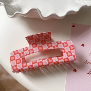 Macro detail of red and pink checkerboard heart pattern on large rectangle hair claw clip
