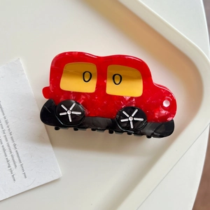 Close-up of red marble pattern car-shaped acetate hair claw clip on a minimal tray