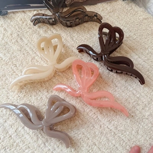 Cinq pinces à cheveux élégantes en forme de ruban en plusieurs coloris sur tissu beige