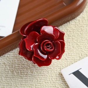 Vue rapprochée d'une pince à cheveux rose 3D en acétate rouge foncé montrant les détails polis