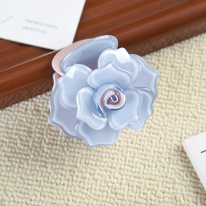 Vue détaillée de la pince à cheveux rose bleue avec fini nacré sur un tapis tressé