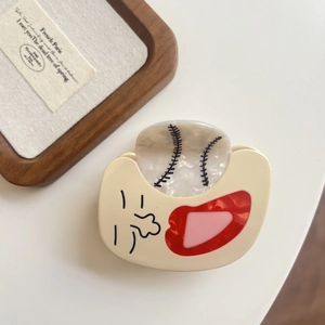 Macro shot of baseball themed hair claw clip with smiling face in cream acetate