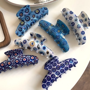 Hanger-shaped evil eye hair claws in various blue and white patterns on white background