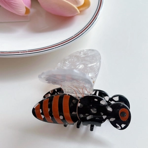 Détail d'une pince à cheveux en forme d'abeille avec des rayures orange et ailes