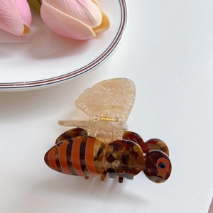 Détail de la pince à cheveux en forme d'abeille avec motif écaille et ressort doré