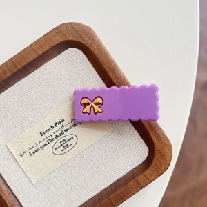 Gros plan détaillé d'une barrette à cheveux violette ondulée avec un nœud doré chic