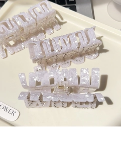 Détail de pinces à cheveux élégantes texture marbre avec perles et strass sur un plateau
