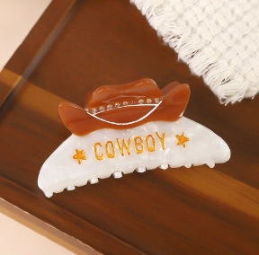 Détail d'une pince à cheveux en acétate avec motif de chapeau de cowboy doré