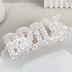 Détail de la pince à cheveux BRIDE avec perles sur un élégant plateau blanc pur