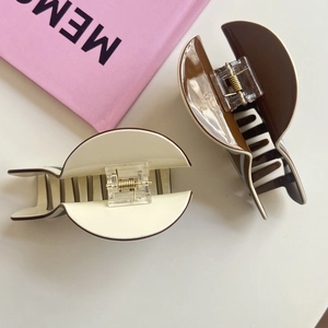 Detailed close-up of large acetate hair claw clips in cream and coffee brown colors