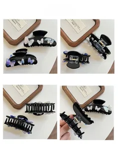 Detailed views of a black acetate shark hair claw with iridescent 3D butterfly accents