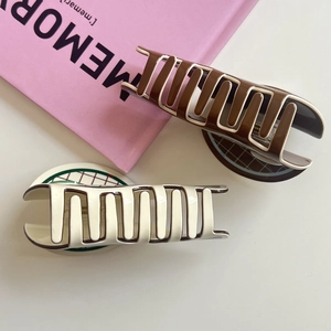 Detail of two large wave-shaped acetate hair claws in brown and cream colors