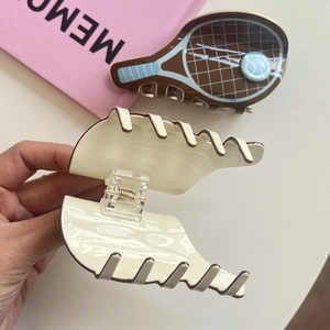 Close-up of tennis racket hair claw clip and cream wavy clip set with metal spring