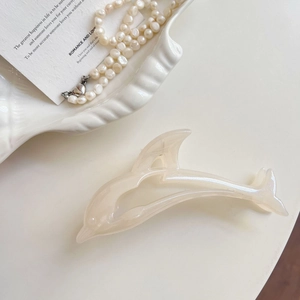 Detail of dolphin hair claw clip in pearl white finish with glossy pearlescent texture