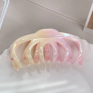 Macro shot of iridescent pink and yellow gradient hair claw clip on ceramic plate