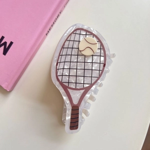 Detail view of acetate tennis racket hair claw with mesh pattern and mini tennis ball