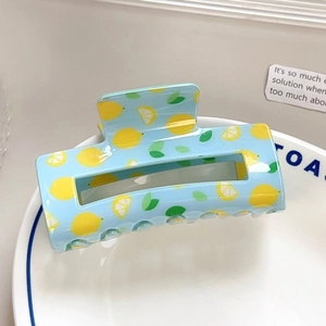 Detail of light blue rectangle hair claw clip with yellow lemon print and hollow design