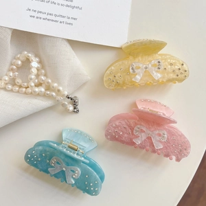 Bow-shaped acetate hair claw clips with rhinestones in aurora pink, yellow, and blue