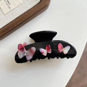 Detail of black butterfly hair claw clip with pink gradient resin and sparkling rhinestones