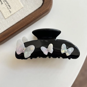Detail shot of black acetate hair claw with shimmering white resin butterflies and rhinestones