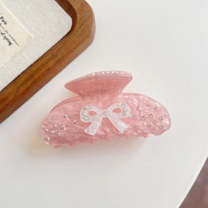 Detailed view of pink acetate hair claw with sparkling glitter and rhinestone bow decoration