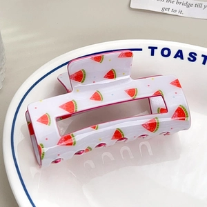 Detailed view of rectangle white hair claw clip with red watermelon patterns on a white plate