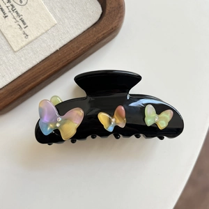Detail of black acetate hair claw clip with iridescent 3D butterfly and rhinestone accents