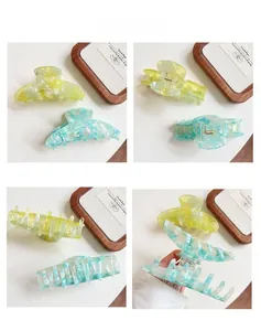 Detail view of large acetate hair claws with marble texture and strong gold metal spring