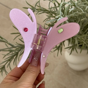 Détail de la pince à cheveux papillon en acétate rose pailleté avec strass colorés