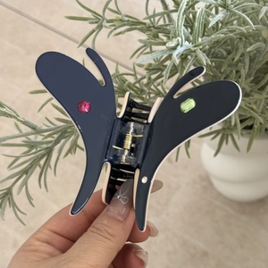 Détail d'une pince à cheveux papillon en acétate bleu ornée de strass multicolores