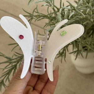 Détail d'une pince à cheveux papillon avec strass colorés et finition blanche scintillante