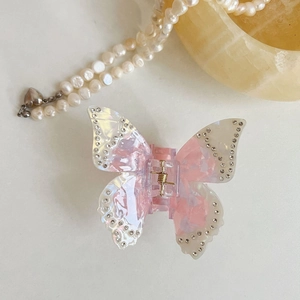 Détail de la pince à cheveux papillon en acétate rose avec strass et ressort doré