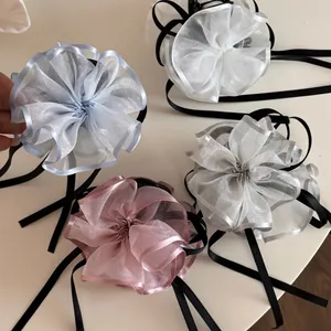 Dettaglio di quattro fermagli a fiore in garza con lunghi nastri blu, bianchi, grigi e rosa