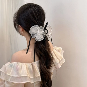 Dettaglio di un fermaglio per capelli con fiocco in organza bianca e nastro nero su capelli