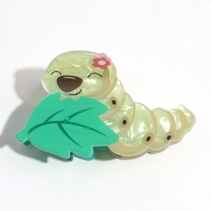 Detail of cute green caterpillar hair claw clip with glossy pearlescent acetate texture