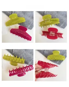 Detailed view of large acetate hair claws in neon green and rose pink with rhinestones