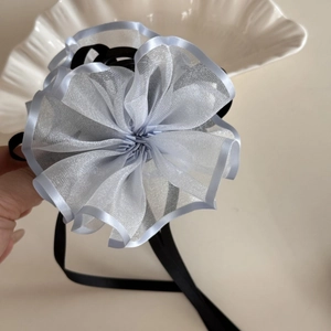 Dettaglio molletta per capelli a fiore in organza azzurra con lunghi nastri di seta nera