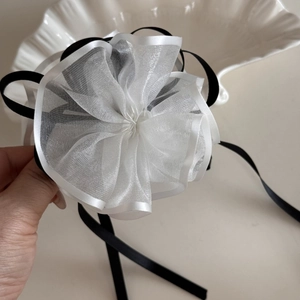 Dettaglio di un fermaglio per capelli a fiori in organza bianca con nastri neri