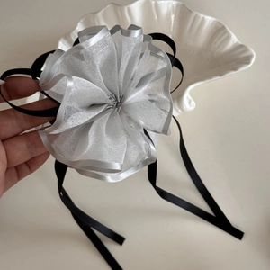 Dettaglio del fermaglio per capelli a fiore grigio con nastri di raso nero e fiocchi