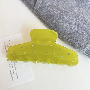 Detail view of a large translucent lime green shark hair clip with sparkling green rhinestones