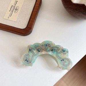 Detail of blue acetate hair claw with silver dragon patterns and blue rhinestones
